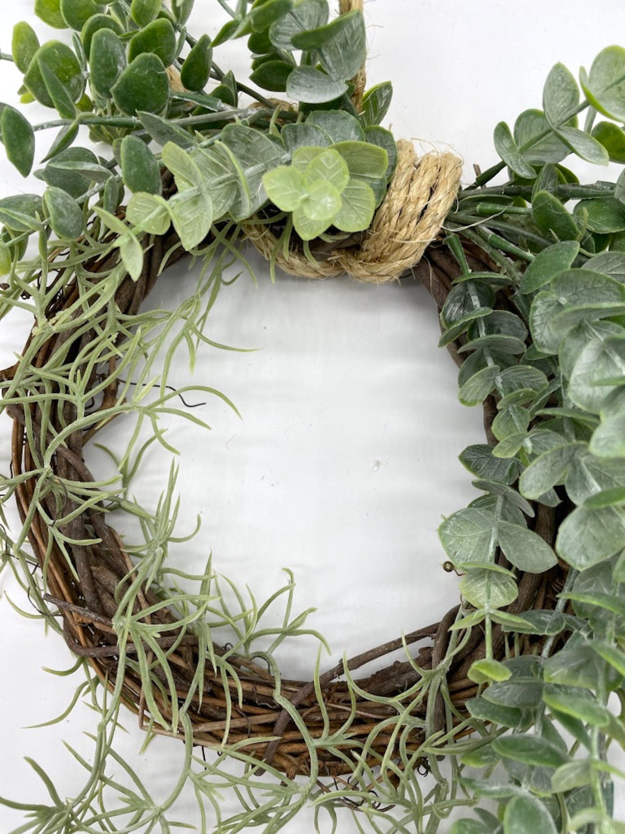 close up for lush handmade eucalyptus wreath with greenery on grapevine base finished with rope to hang wreath on wall or door