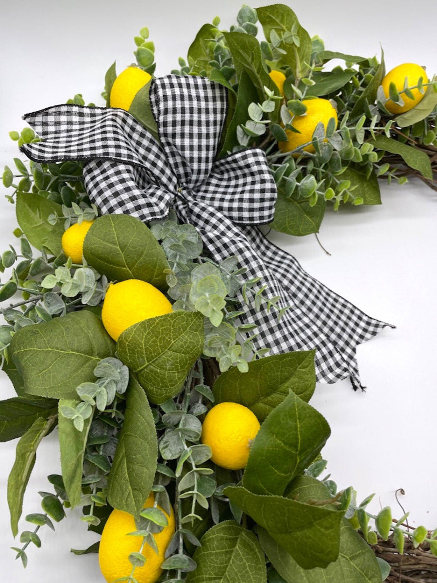 lemon wreath with green leaves and eucalyptus stems on grapevine round base decorated with black and white checkered bow