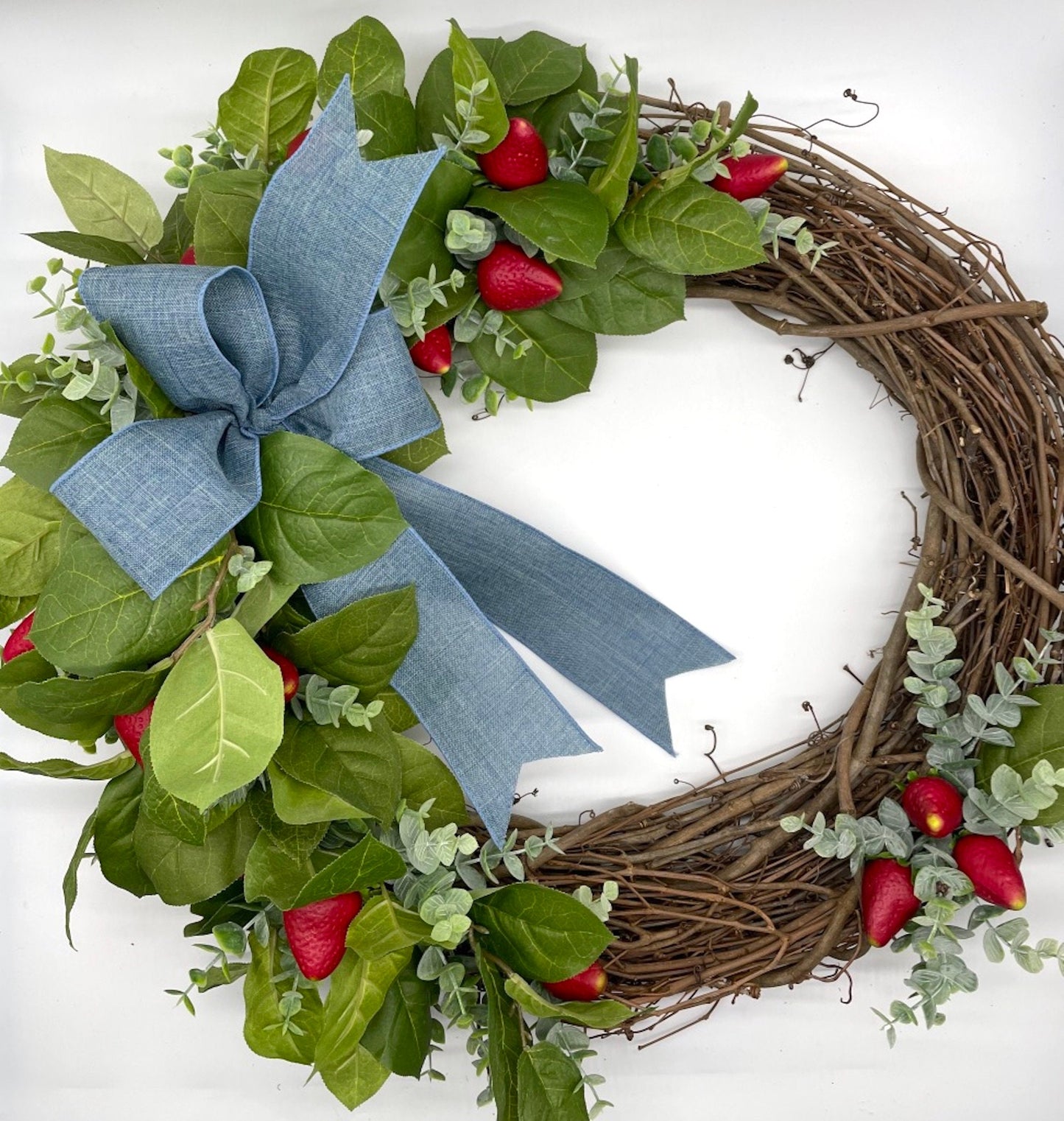 realistic strawberry wreath with greenery and faux berries on a round grapevine base and periwinkle bow